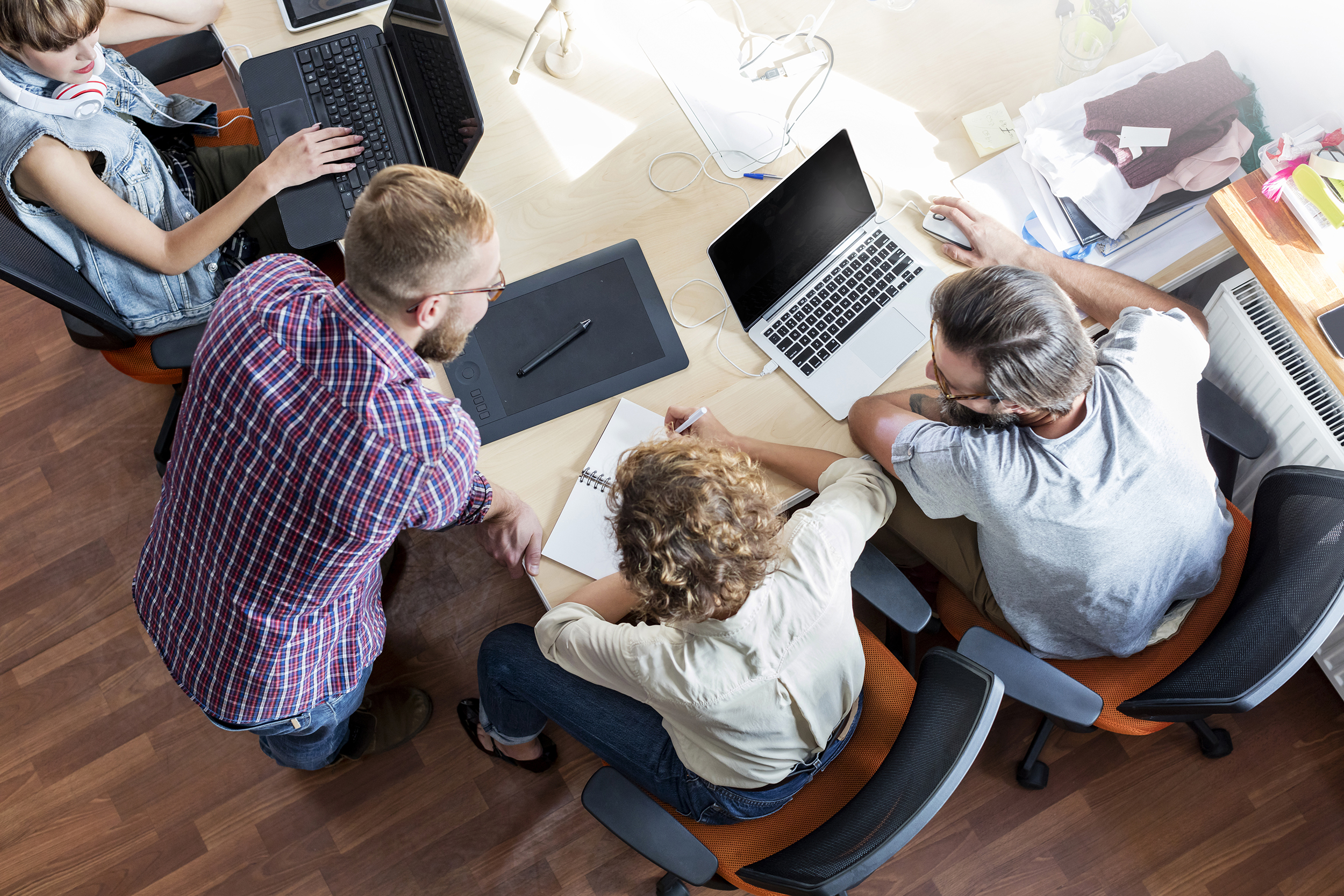 Overhead view design professionals working at laptops in meeting